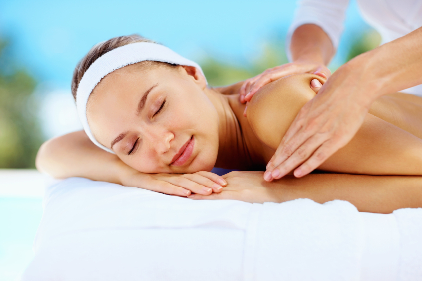Relaxed young woman receiving shoulder massage from a professional masseuse